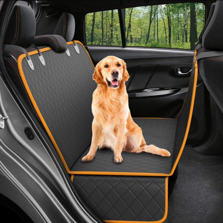 Dog sitting on a car seat cover in a vehicle with a forest view outside.