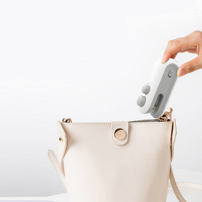 Hand holding a mini bag sealer next to an open beige handbag on a white background