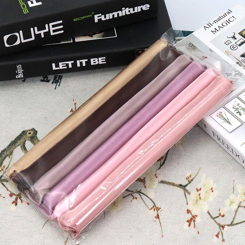 Set of Hair Curling Rod Set in brown, pink, and purple on a floral-patterned surface with books in the background.