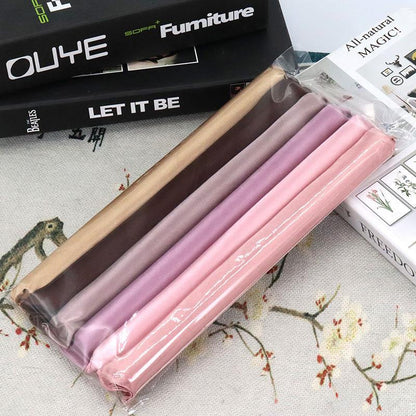 Set of Hair Curling Rod Set in brown, pink, and purple on a floral-patterned surface with books in the background.